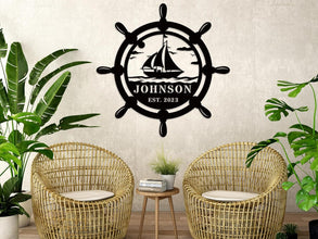 Custom nautical metal sign featuring a ship wheel and sailboat design with personalized name and year, ideal for coastal wall décor