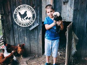 Round custom metal chicken coop sign with a hen and two chicks, personalized with family name and established date, made from durable black steel.