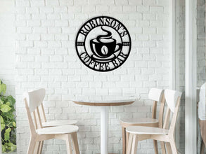 Custom coffee bar metal sign featuring a steaming cup and personalized name text, laser-cut from premium steel with powder-coated black finish.
