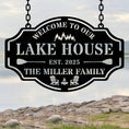 Custom metal lake house sign with family name, trees, paddles, and chairs design, black powder-coated steel, personalized outdoor cabin wall decor.