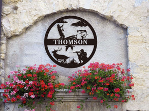 Custom round black metal hunting and fishing sign featuring a fisherman, deer, hunter silhouette, and personalized family name – laser-cut from powder-coated steel for outdoor wall decor.