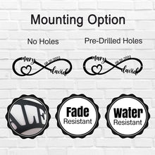 Personalized infinity heart metal sign with custom names and date, laser-cut from black powder-coated steel, displayed against a white brick wall.