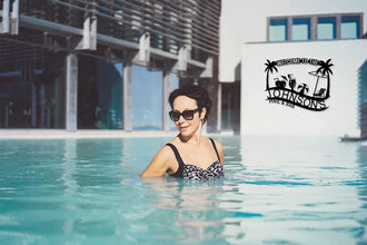 Customizable black metal sign with a tropical design, featuring palm trees, a beach umbrella, lounge chair, beach ball, and cocktails, with