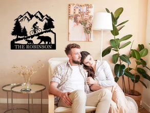 Custom bicycle metal sign with mountain and bear design, personalized family name cycling wall art, laser cut steel décor for rustic home or outdoor cabin.