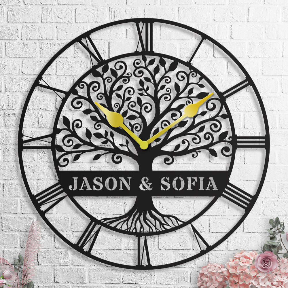 Large personalized black metal wall clock featuring an intricate tree of life design with custom names, optional Roman or Arabic numbers, and elegant hands. Main image