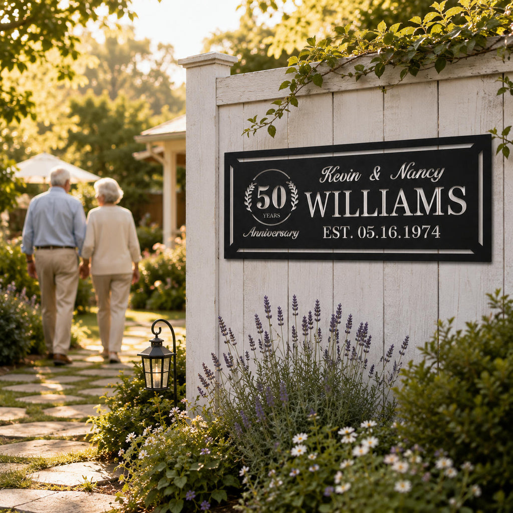 Personalized 50th anniversary metal sign displayed on a white garden fence surrounded by flowers and landscaping.