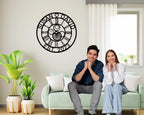Large personalized black metal wall clock with laser-cut cutout gears, couple names Jason and Laura, center heart icon, established 2023, and Roman numerals.
