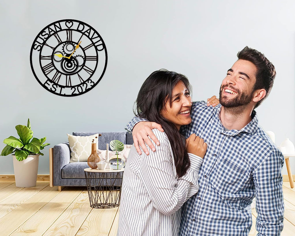 Large personalized black metal wall clock with laser-cut cutout gears, couple names Jason and Laura, center heart icon, established 2023, and Roman numerals.