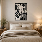 Modern black iron abstract face wall decor above a cozy bedroom bed with neutral interior design