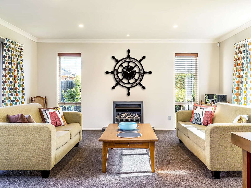 Large personalized black metal wall clock shaped like a ships wheel, featuring laser-cut cutout name Thomas, custom GPS coordinates, and Arabic numbers.