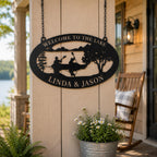 Black powder coated metal lake house sign hanging on a rustic porch post with lake view and outdoor decor