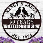 Custom round metal anniversary sign featuring personalized names, years together, and lovebirds on a branch.