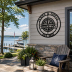 Personalized compass metal wall sign displayed on lake house exterior wall overlooking waterfront scenery
