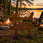Weathered steel yard sign displayed beside a lakeside campfire seating area.