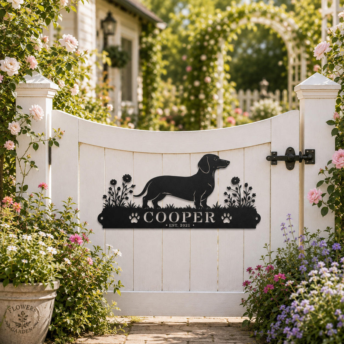 Decorative Dachshund personalized metal sign displayed on a white garden gate with blooming flowers.
