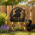 Personalized dachshund metal yard sign displayed on a wooden fence with a dachshund standing nearby.