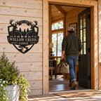 Custom deer lodge metal sign beside an open cabin door as a guest arrives carrying a duffel bag.