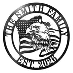 A matte black laser-cut circular metal art monogram, made of heavy-duty 14-gauge steel, featuring a majestic bald eagle profile and waving American flag. The top arc reads "THE SMITH FAMILY" and the bottom arc reads "EST. 2026", both cut-out text. This is an example of a customizable family name sign.