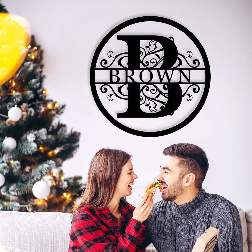 Black circular metal monogram sign with custom family name and botanical patterns.