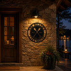 Personalized round metal lake house sign illuminated by warm porch lighting at night, custom outdoor wall decor for waterfront cabin entrance.