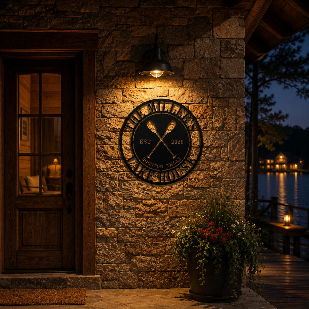 Personalized round metal lake house sign illuminated by warm porch lighting at night, custom outdoor wall decor for waterfront cabin entrance.
