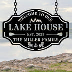 Custom metal lake house sign with family name, trees, paddles, and chairs design, black powder-coated steel, personalized outdoor cabin wall decor.