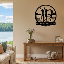 Custom lake kids metal sign featuring children silhouette design, personalized family name and year, round steel wall decor for lake house or cabin