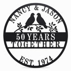 Custom round metal anniversary sign with two lovebirds on branches, personalized with names, years together, and established date.