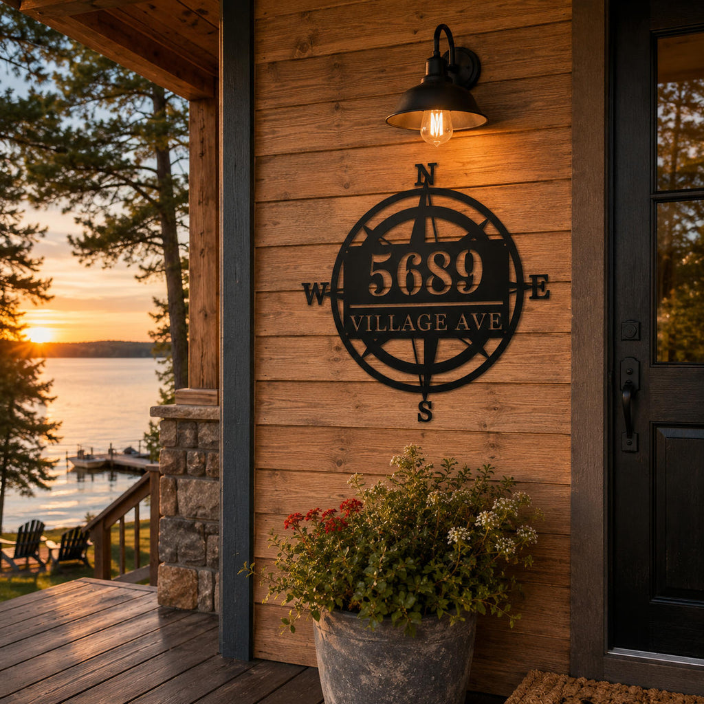 Custom metal compass address sign mounted on a rustic American lake house at sunset.