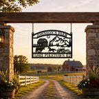 Custom metal farm sign hanging from a rustic wooden farm entrance with stone pillars, white fencing, and countryside barn at sunset.