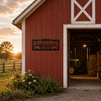 Personalized farm name metal sign installed above a traditional red barn entrance.