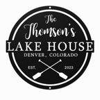Personalized black metal lake house sign with family name, location, established year, and crossed paddle design on a white background.