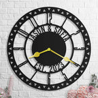Large personalized black metal wall clock with geometric triangle border, featuring laser-cut cutout family names, established year, and optional numeric styles.