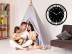 Large personalized black metal wall clock with a solid center dial, featuring laser-cut cutout family names, established 2023, and modern Arabic numbers.