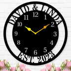 Large personalized black metal wall clock with a solid center dial, featuring laser-cut cutout family names, established 2023, and modern Arabic numbers.