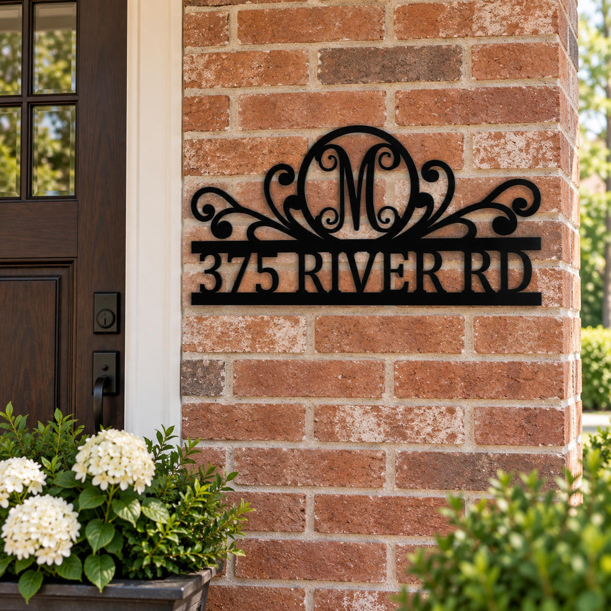 Custom black metal monogram address sign mounted beside the entrance of a red brick home.