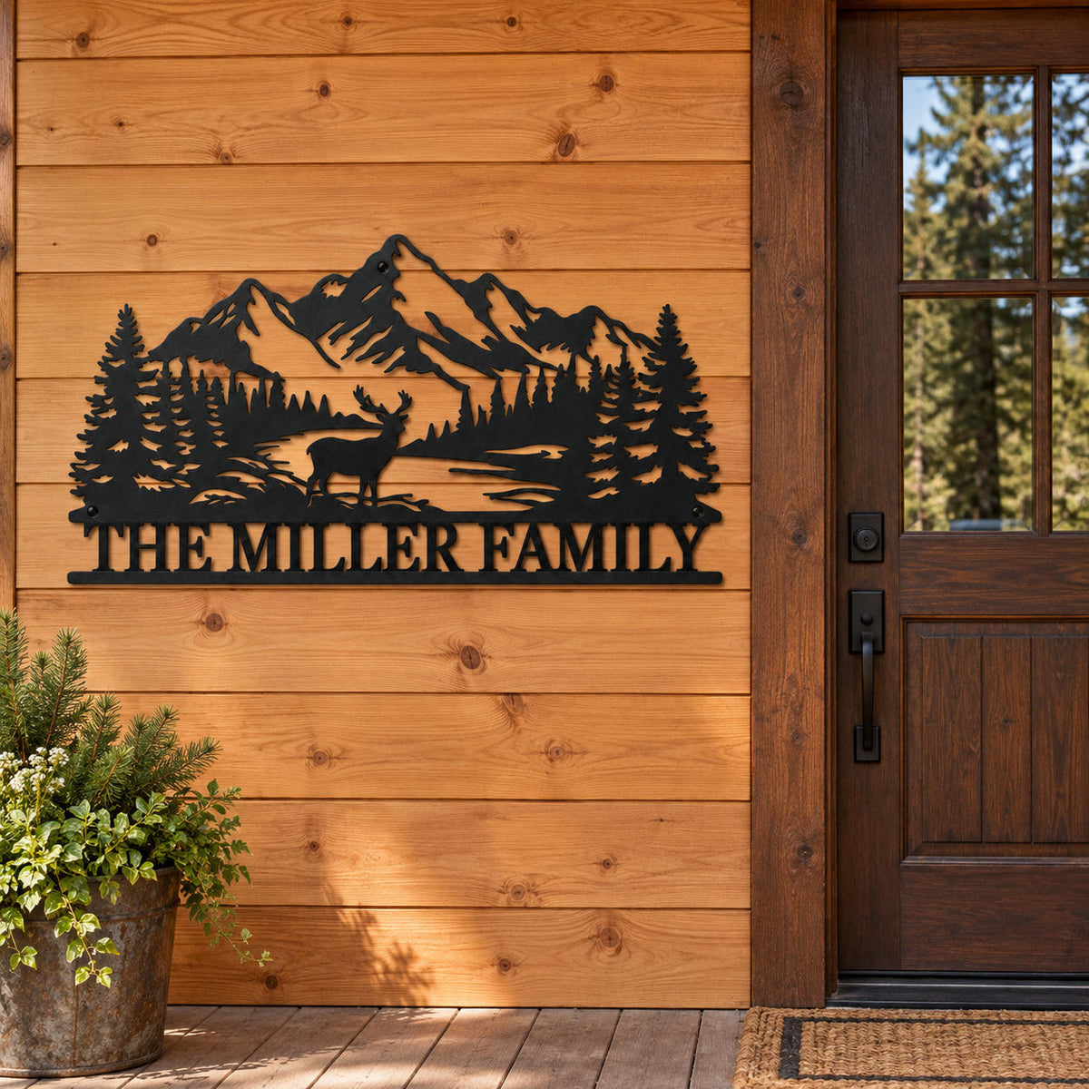 Personalized mountain and deer metal sign mounted on cedar siding beside a wooden cabin entrance door.