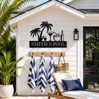 Custom tropical metal pool sign mounted on a white pool house wall, personalized outdoor steel sign for backyard pool area.