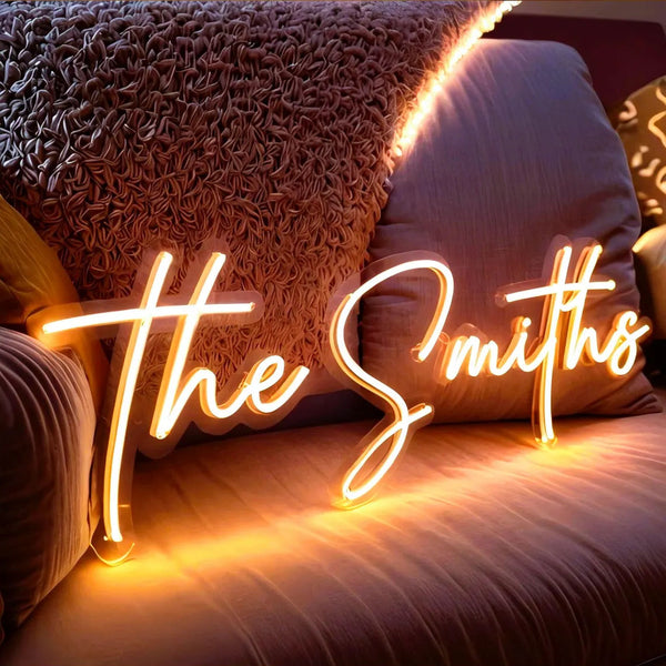 Custom script neon sign glowing in warm amber light with personalized text, decorative LED neon sign for bedroom and home décor, customizable font size and color