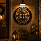 Black metal family tree sign illuminated by warm porch lighting at night