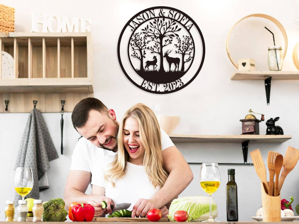 Customizable round black metal sign with a laser-cut design featuring a buck and a doe in a forest of trees. The top text reads "JASON & SOFIA" and the bottom text reads "EST. 2023".