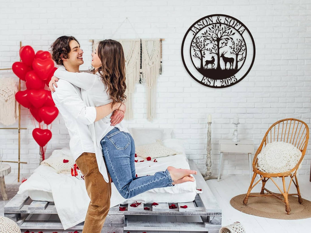 Customizable round black metal sign with a laser-cut design featuring a buck and a doe in a forest of trees. The top text reads "JASON & SOFIA" and the bottom text reads "EST. 2023".