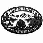 Black oval metal camping wall sign with mountain, lake, couple, campfire, and off-road vehicle design on a white background.