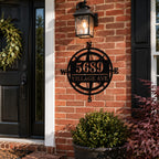 Personalized metal compass house number sign mounted on a classic red brick home exterior.