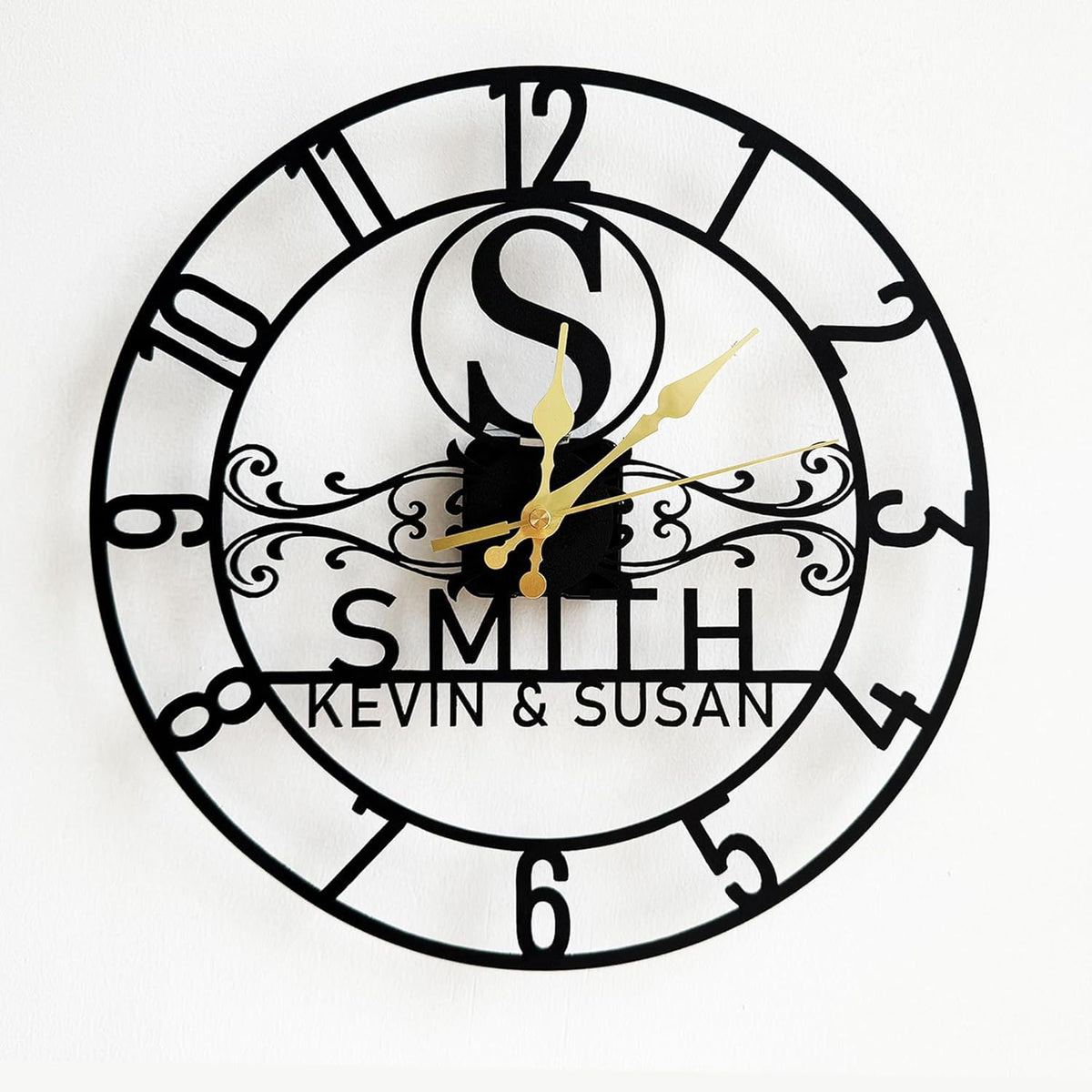 Personalized black steel wall clock with Arabic numerals, gold hands, and custom family names.