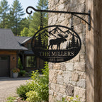 Personalized moose family metal sign hanging from a black metal bracket outside a rustic stone home.