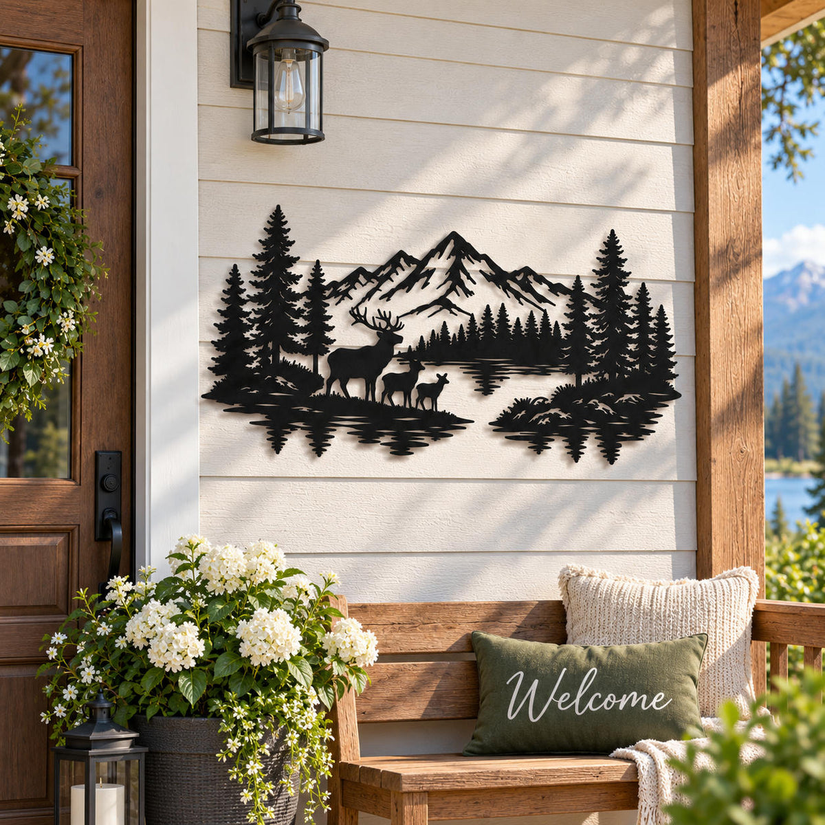 Black metal mountain and deer wall art displayed on a covered porch beside a rustic cabin entryway.