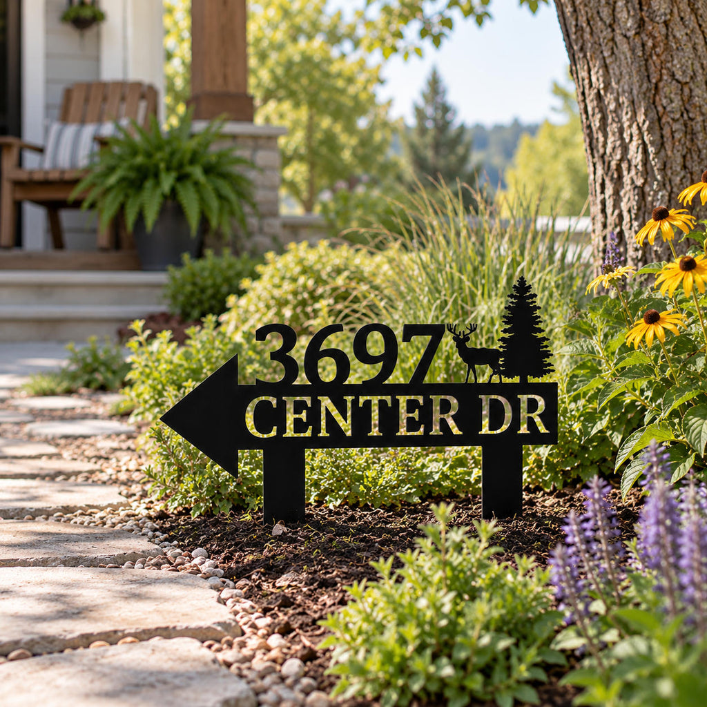 Personalized black metal address sign with a left-pointing arrow installed beside a garden walkway.