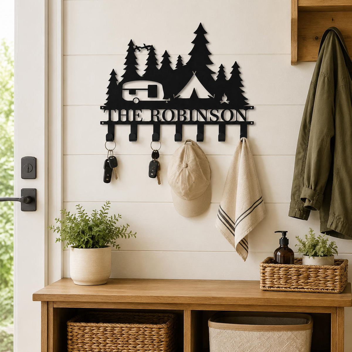 Personalized camping metal key holder mounted in a farmhouse entryway with keys, a cap, and a light towel.