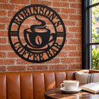 Personalized coffee bar metal sign on a red brick wall above a caramel leather café booth, with a cappuccino and an open book on the table.